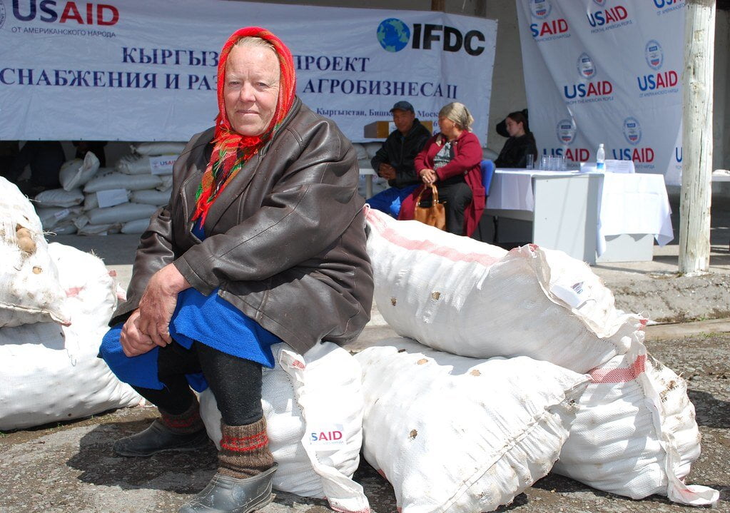 babka sedí na vreciach so zemiakmi