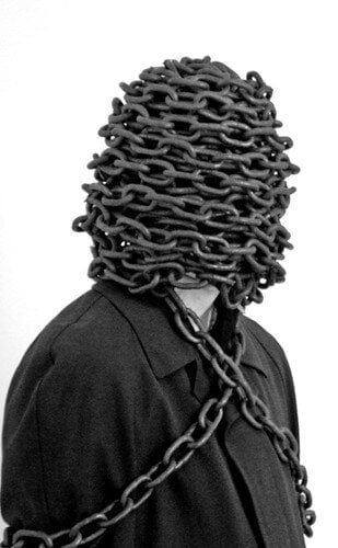 hlava človeka obalená reťazami