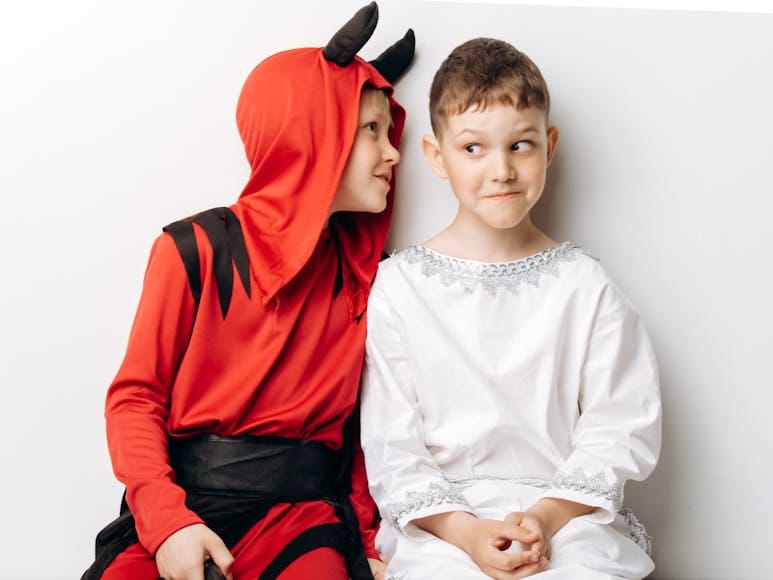 Two children in devil and angel costumes having fun during Halloween.